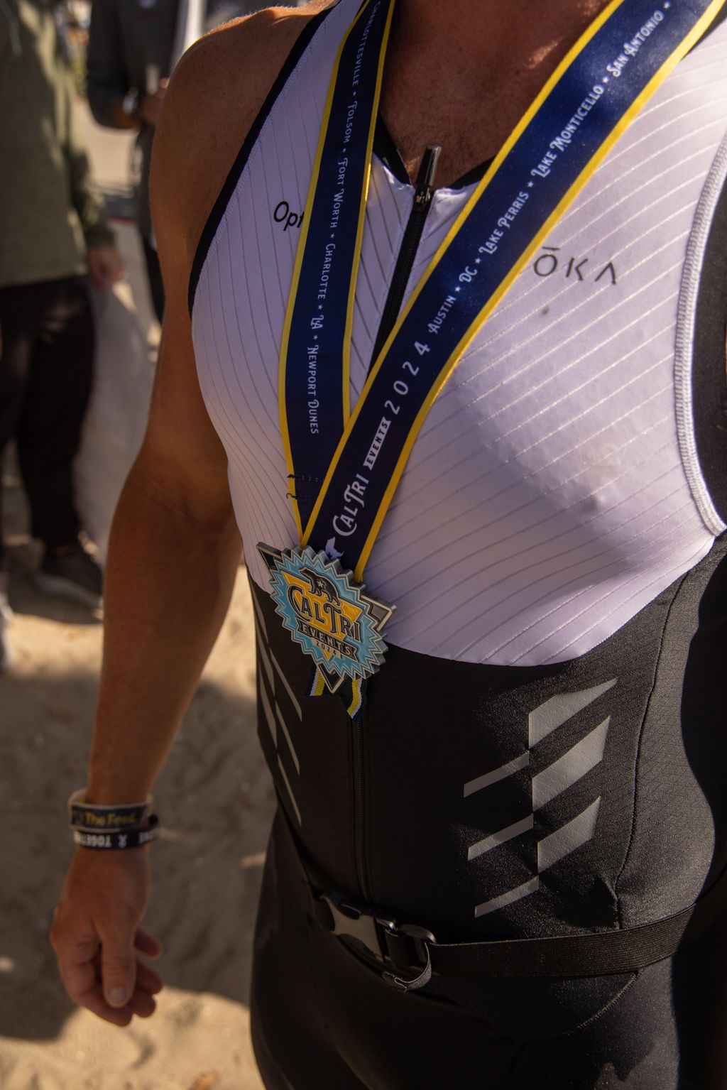 Cal Tri Events finisher medal on an athlete in an Optimism race kit